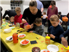 families making pumpkin luminaries with orange tissue paper and Mason jars
