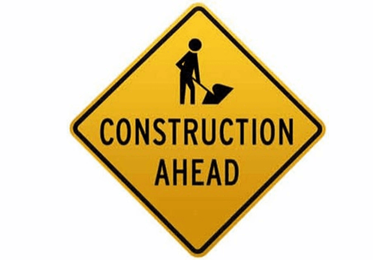 yellow diamond shape sign saying construction ahead
