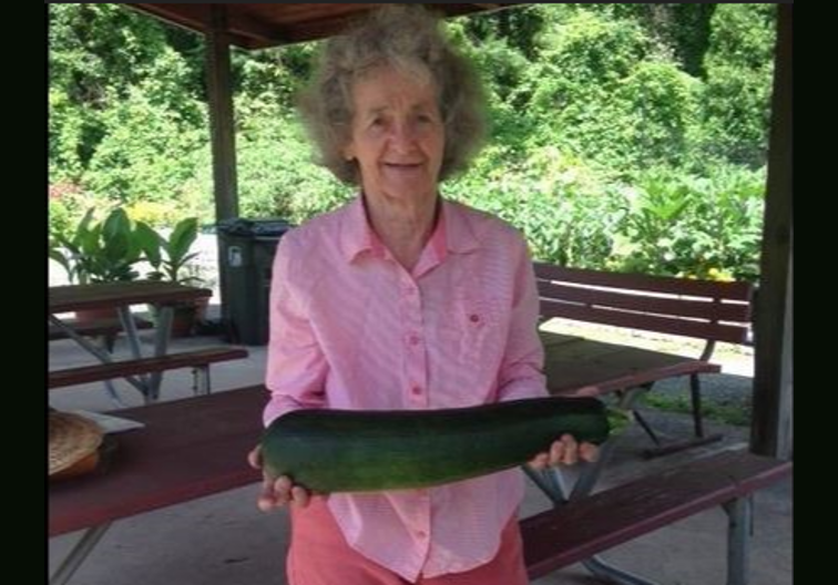 A member displays a zucchini grown in the community garden