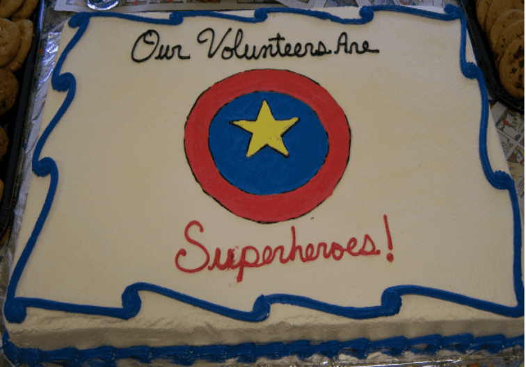 A sheet cake with 'Our Volunteers Are Superheroes!' written in frosting
