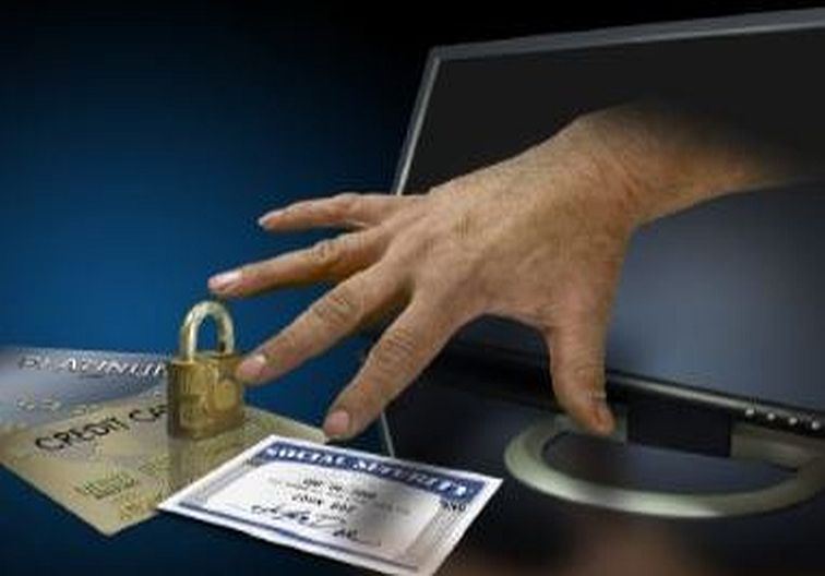 Hand holding credit cards with a lock and a computer in the background