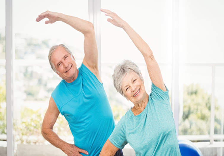 Photograph of two older adults streching thier arms over thier heads in exercise