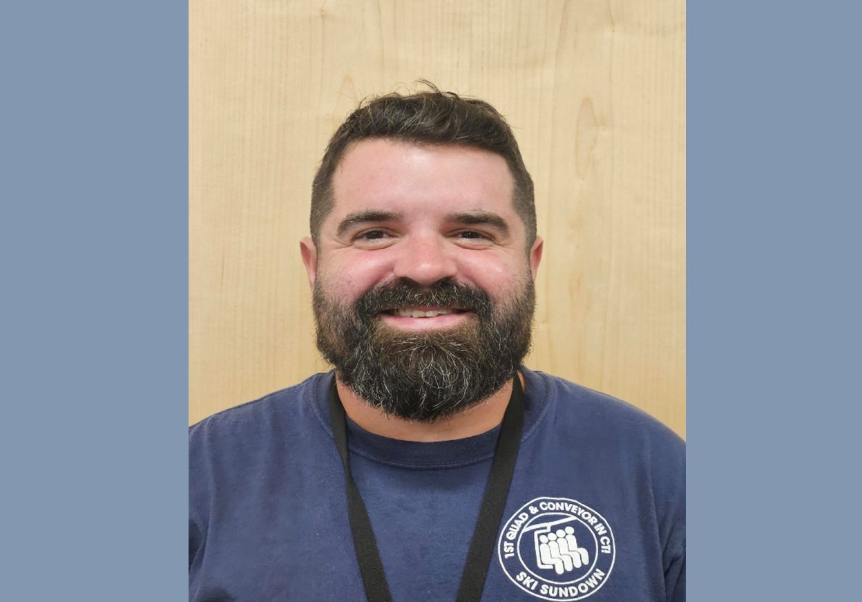 Picture of caucasian male with dark short hair & beard - wearing blue tee shirt.